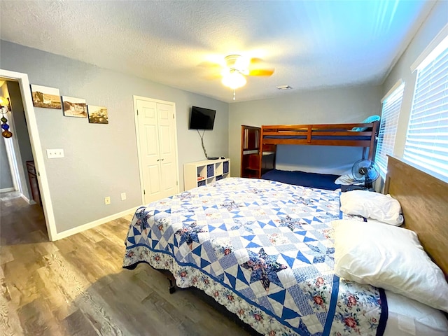 bedroom with wood-type flooring, a closet, a textured ceiling, and ceiling fan