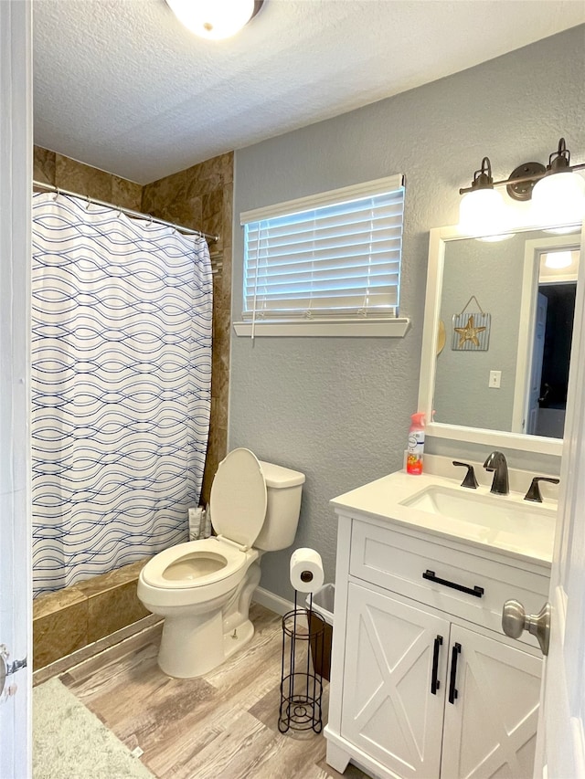 bathroom featuring toilet, hardwood / wood-style floors, a shower with shower curtain, vanity, and a textured ceiling