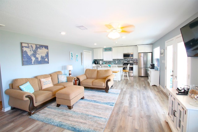 living room with ceiling fan and light hardwood / wood-style flooring