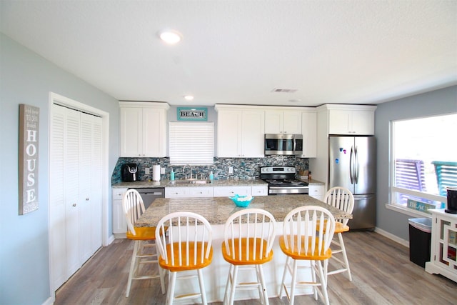2619 Swan Ct, Surfside Beach, TX 77541 - kitchen with stainless steel appliances, a kitchen island, decorative backsplash, and a kitchen breakfast bar