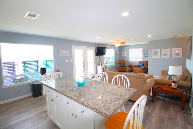 2619 Swan Ct, Surfside Beach, TX 77541 - kitchen featuring a breakfast bar area, white cabinetry, light wood-type flooring, open floor plan, and french doors