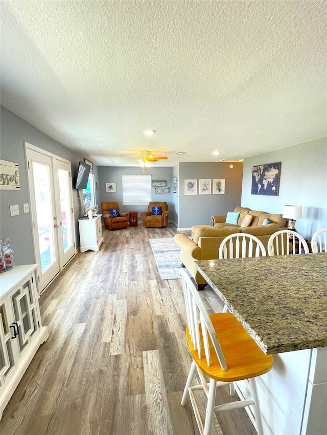 dining area with french doors, hardwood / wood-style floors, a textured ceiling, and ceiling fan