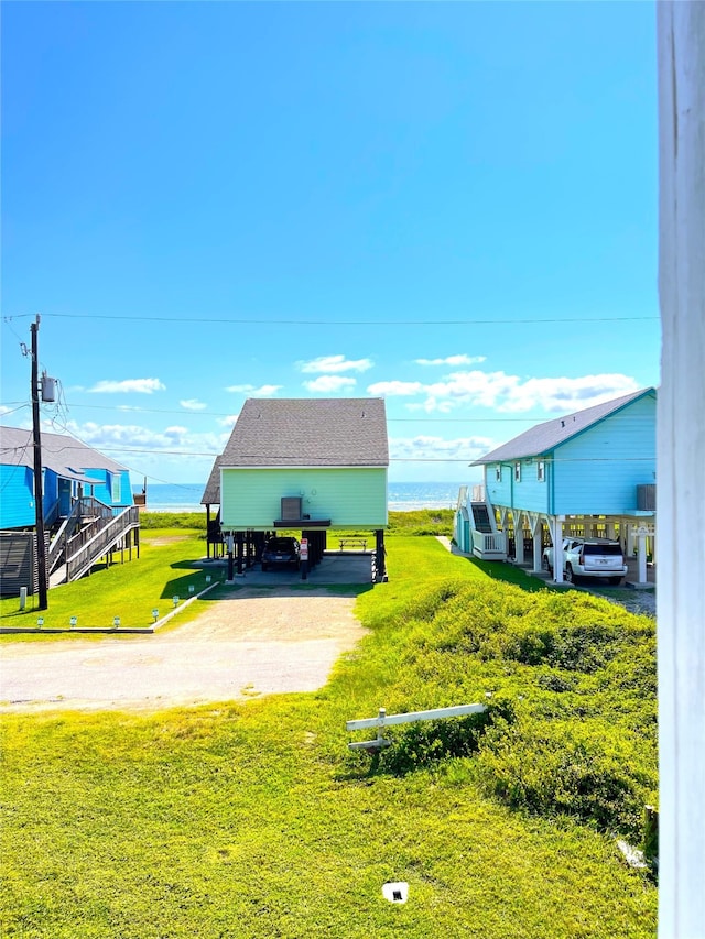 view of community featuring a water view, a carport, and a lawn