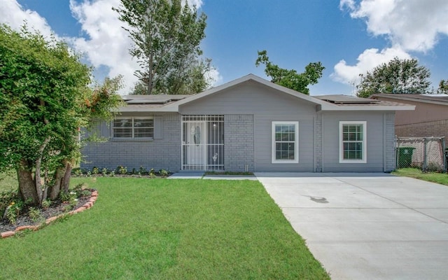 single story home with a front lawn and solar panels