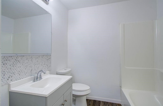 bathroom with wood-type flooring, vanity, toilet, and backsplash