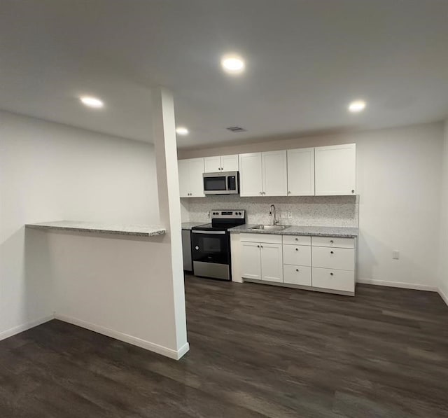 kitchen with sink, appliances with stainless steel finishes, tasteful backsplash, white cabinets, and dark wood-type flooring