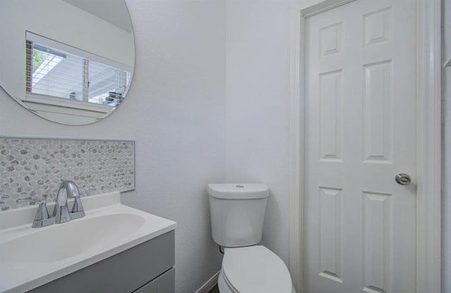 bathroom with vanity, toilet, and backsplash