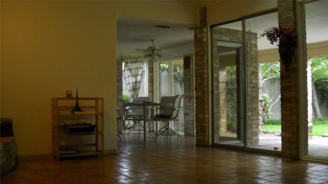 doorway to outside with ceiling fan and dark tile patterned flooring