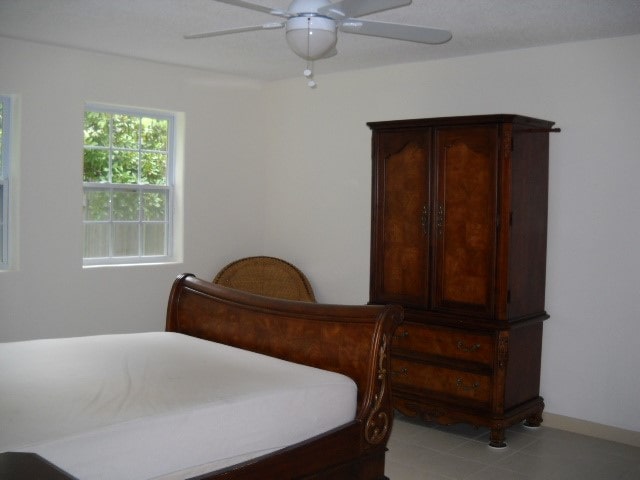 bedroom with ceiling fan and light tile patterned flooring