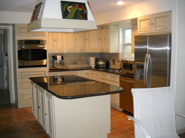 kitchen with custom exhaust hood, sink, tasteful backsplash, a kitchen island, and appliances with stainless steel finishes