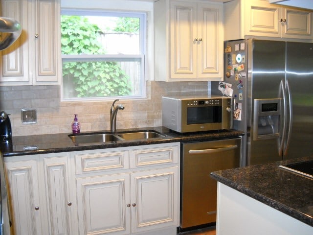 kitchen with decorative backsplash, white cabinets, dark stone countertops, sink, and appliances with stainless steel finishes