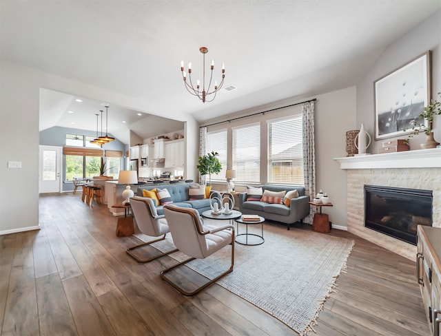 living room featuring lofted ceiling, a chandelier, dark wood-type flooring, and a fireplace