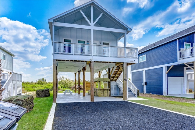 1052 Johnson Rd, Gilchrist, TX 77617 - coastal home with a carport, board and batten siding, stairway, and gravel driveway