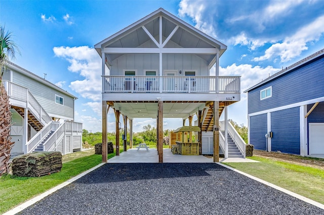 1052 Johnson Rd, Gilchrist, TX 77617 - coastal inspired home with stairs, board and batten siding, a carport, driveway, and a front yard