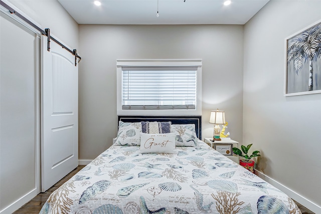 bedroom with a barn door and dark wood-type flooring