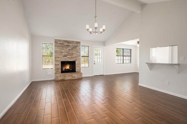 unfurnished living room featuring a stone fireplace, dark hardwood / wood-style flooring, high vaulted ceiling, and ceiling fan with notable chandelier