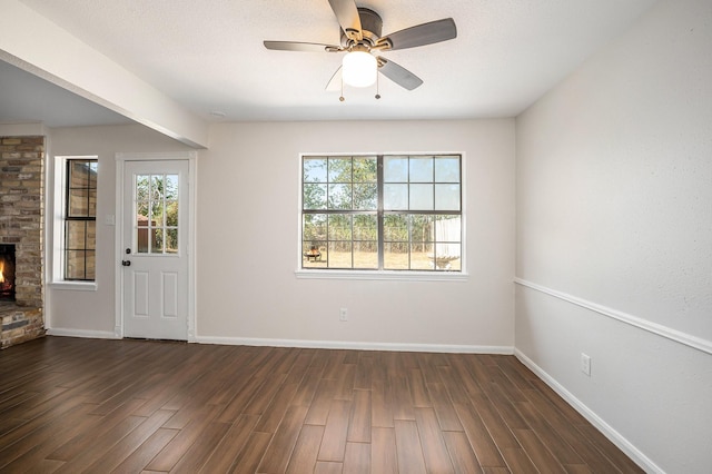 unfurnished room with dark hardwood / wood-style floors, ceiling fan, and a brick fireplace