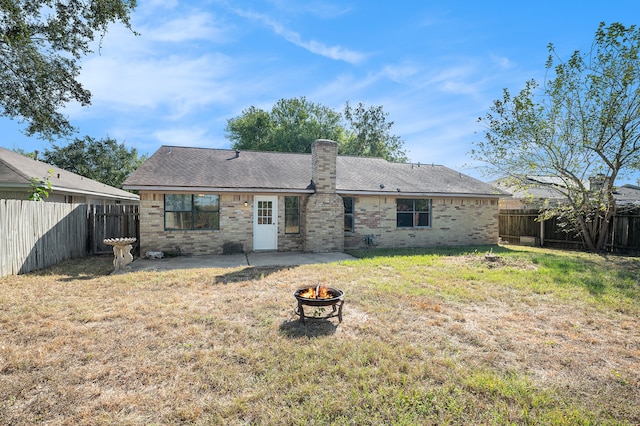 back of house with a fire pit and a lawn