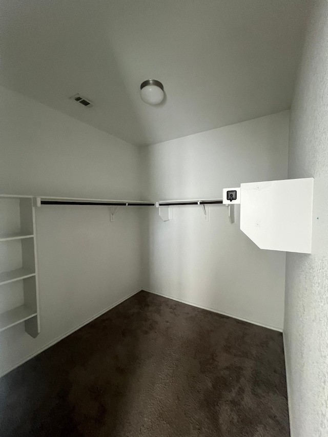 walk in closet with dark colored carpet