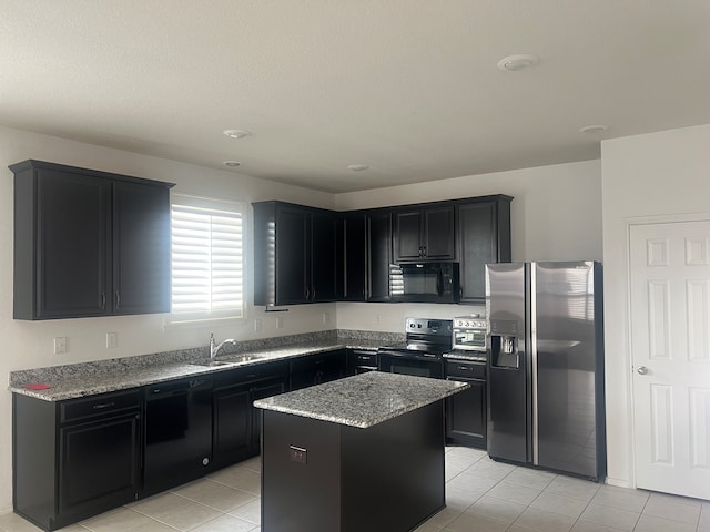 kitchen with black appliances, light tile patterned floors, light stone countertops, sink, and a center island