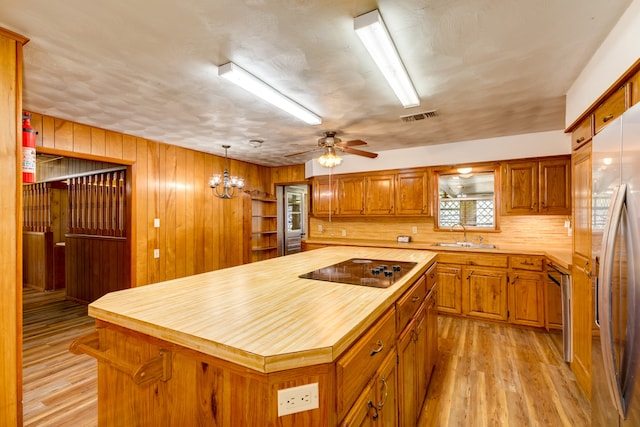 kitchen with light wood-type flooring, a center island, sink, pendant lighting, and appliances with stainless steel finishes