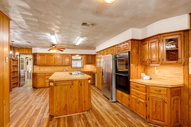 kitchen featuring ceiling fan, tasteful backsplash, black appliances, a center island, and light wood-type flooring