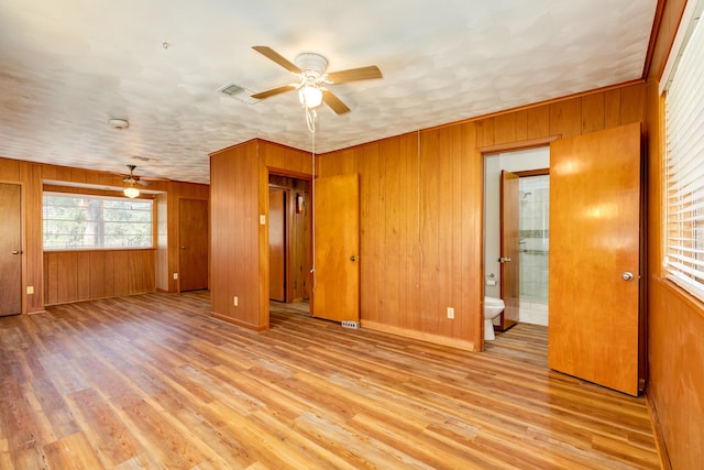 interior space featuring ceiling fan, wood walls, and light hardwood / wood-style flooring