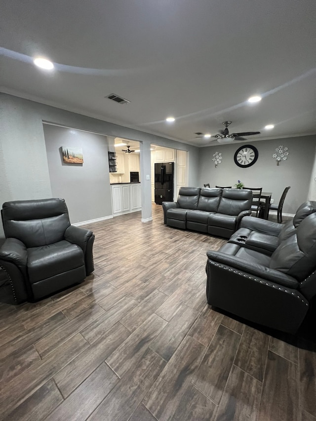 living room with wood-type flooring, crown molding, and ceiling fan