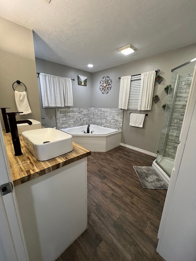 bathroom featuring separate shower and tub, hardwood / wood-style flooring, vanity, and a textured ceiling