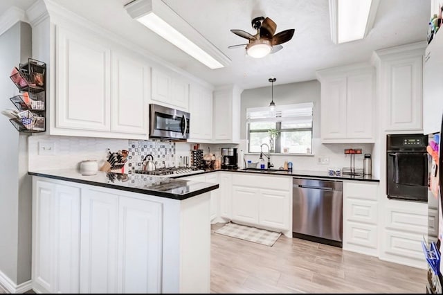 kitchen featuring sink, decorative backsplash, kitchen peninsula, appliances with stainless steel finishes, and white cabinetry