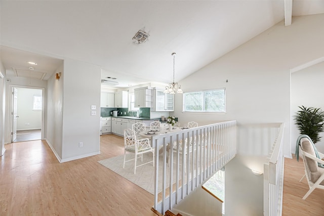 dining room featuring vaulted ceiling with beams, sink, a notable chandelier, and light wood-type flooring