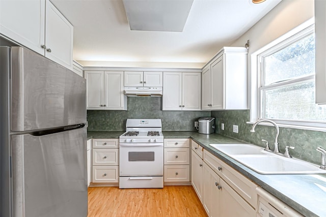 kitchen with decorative backsplash, white appliances, sink, and light hardwood / wood-style flooring