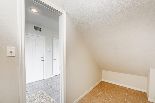 bonus room featuring a textured ceiling, light tile patterned flooring, and vaulted ceiling