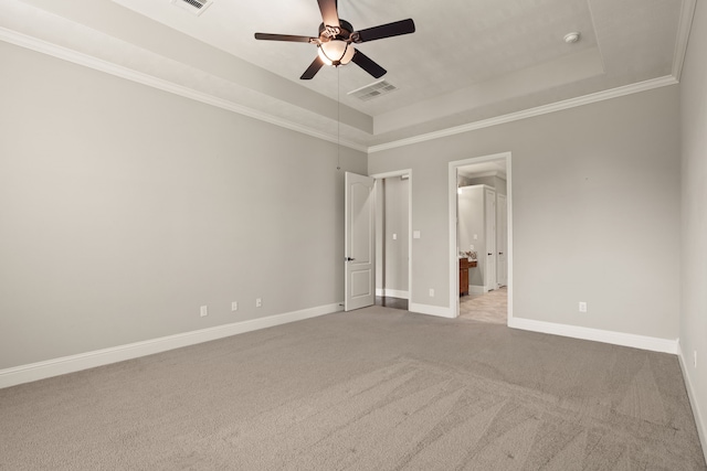 unfurnished bedroom with ornamental molding, a tray ceiling, light colored carpet, and ceiling fan