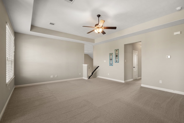 carpeted spare room featuring ceiling fan and a raised ceiling