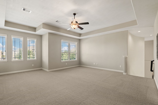 carpeted empty room with ceiling fan and a tray ceiling