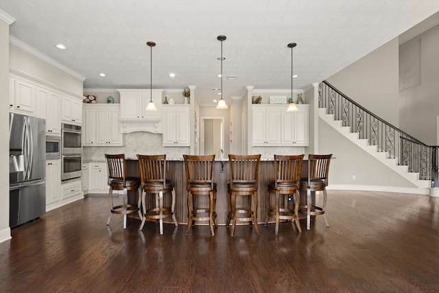 kitchen with appliances with stainless steel finishes, hanging light fixtures, a center island with sink, and dark hardwood / wood-style flooring