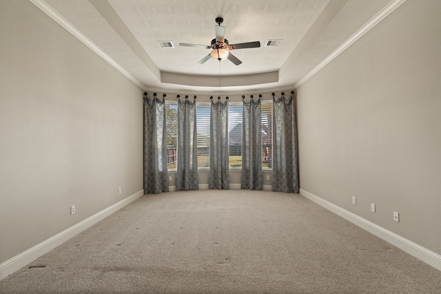 carpeted spare room featuring crown molding, ceiling fan, and a raised ceiling