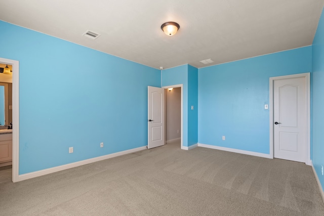 unfurnished bedroom with connected bathroom and light colored carpet