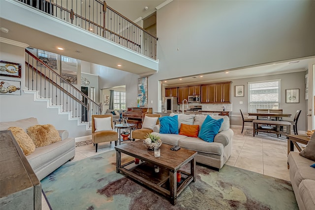 living room with a high ceiling, crown molding, and light tile patterned floors