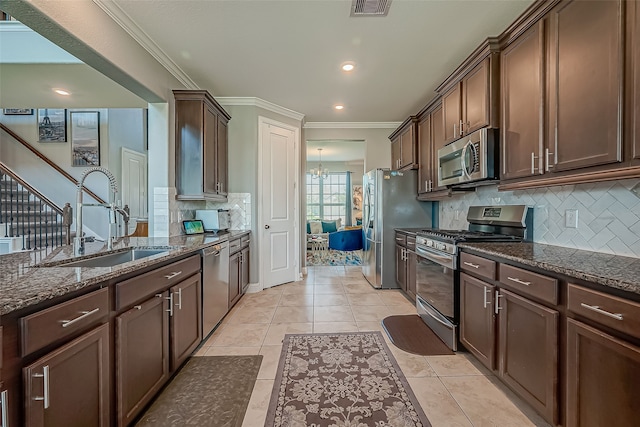 kitchen with appliances with stainless steel finishes, dark stone counters, sink, and ornamental molding