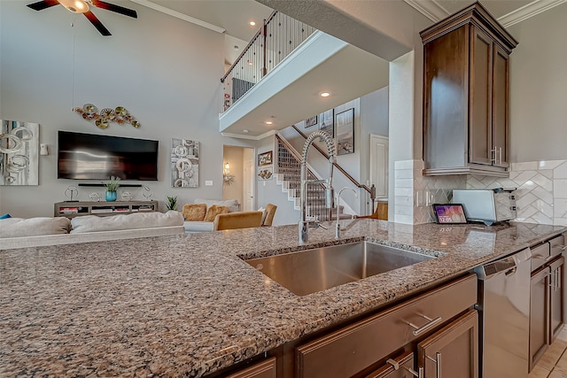 kitchen featuring sink, crown molding, dishwasher, dark stone countertops, and a towering ceiling