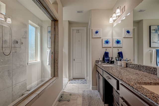 bathroom with tile patterned floors, tiled shower, and vanity