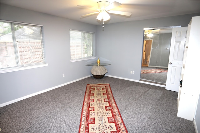 interior space featuring ceiling fan and dark carpet