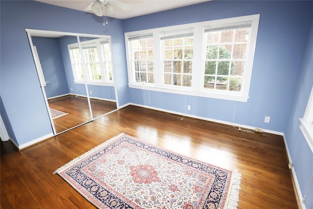 unfurnished bedroom with a closet, dark hardwood / wood-style flooring, and ceiling fan