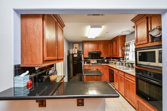 kitchen with black appliances, decorative backsplash, a kitchen breakfast bar, sink, and light tile patterned floors