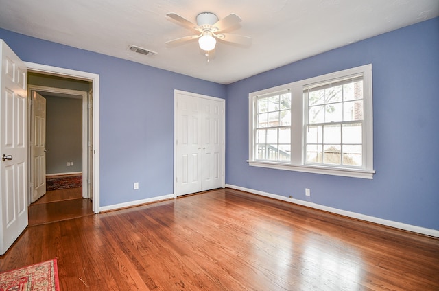 unfurnished bedroom featuring hardwood / wood-style flooring, ceiling fan, and a closet