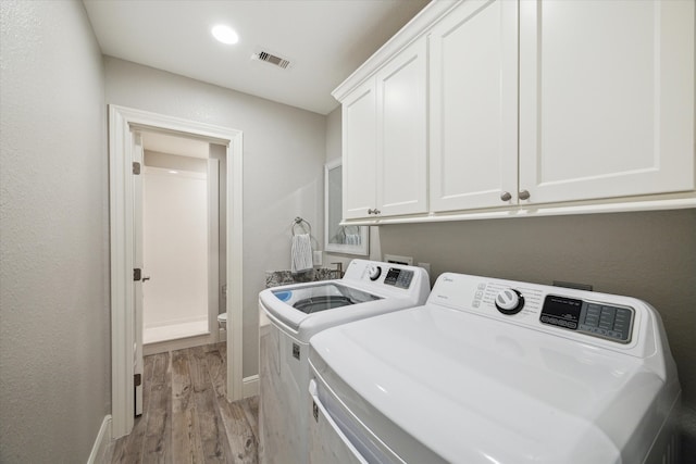 washroom with washer and clothes dryer, cabinets, and light hardwood / wood-style flooring