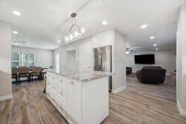 kitchen with light hardwood / wood-style floors, decorative light fixtures, a kitchen island, and white cabinetry