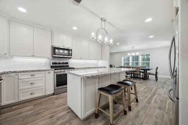 kitchen featuring light wood-type flooring, appliances with stainless steel finishes, white cabinets, and a center island